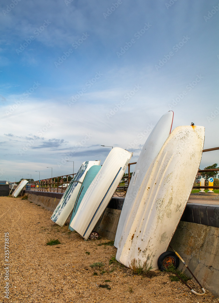 Dinghy resting against a wall on UK beach Dinghy resting against a wall on UK beach