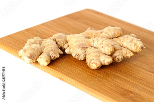 Ginger root on wooden cutting board isolated on white background