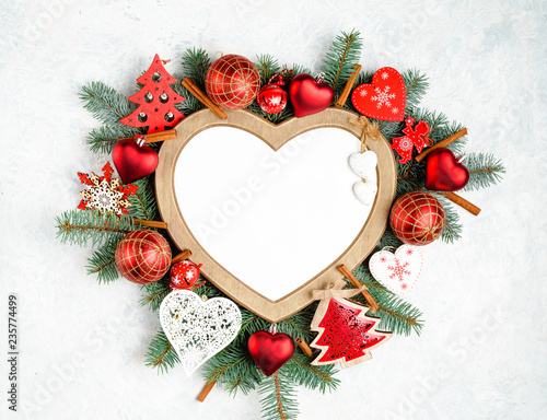 Christmas frame in the shape of a heart is surrounded by branches of a New Year tree Christmas decorations with copy space. Top view, flat lay. Nature New Year concept.