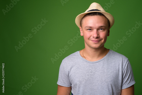 Studio shot of young handsome tourist man against green backgrou