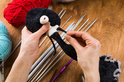 A woman knits a wool toy with hook. Hands close-up.
