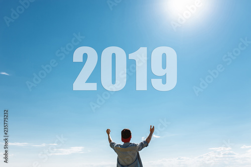 Man, against the blue sky, the guy pulls hands to the sky, the concept of the new 2019 year.