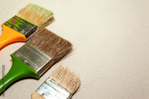 three paint brushes of different sizes lie on a smooth light surface