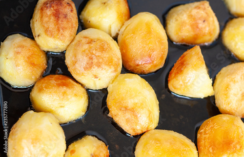 Crispy roast potatoes sizzling away in a baking tray
