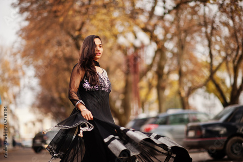 Pretty indian girl in black saree dress posed outdoor at autumn street.