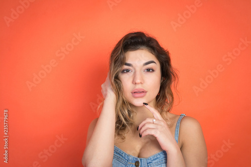 portrait of beautiful girl with curly hair in jeans clothes on red background