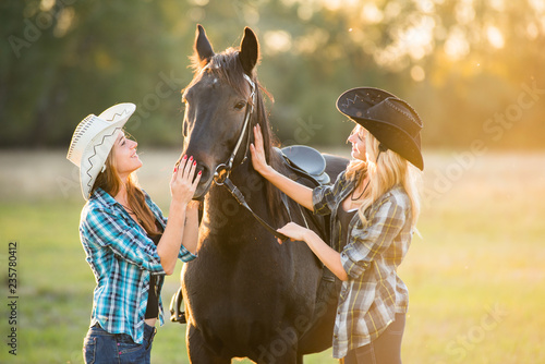Jeździec dwóch dziewczyn stoi w pobliżu konia. Motyw konia