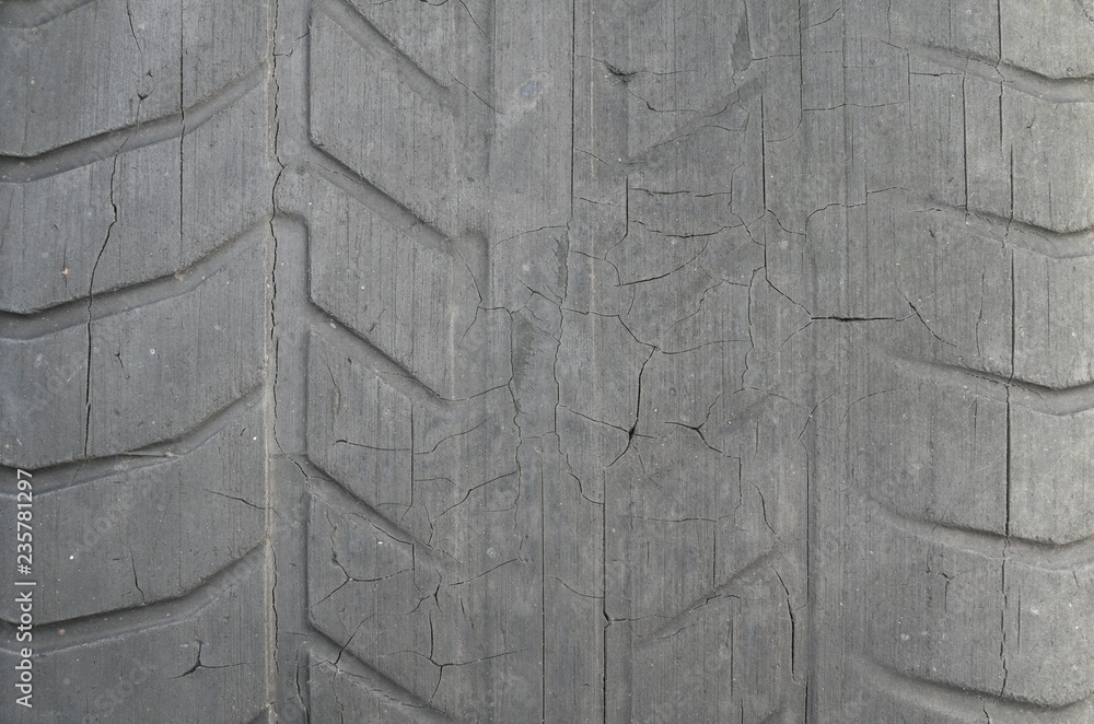 Foto de Old black tire with worn tread and cracks, worn old car tire