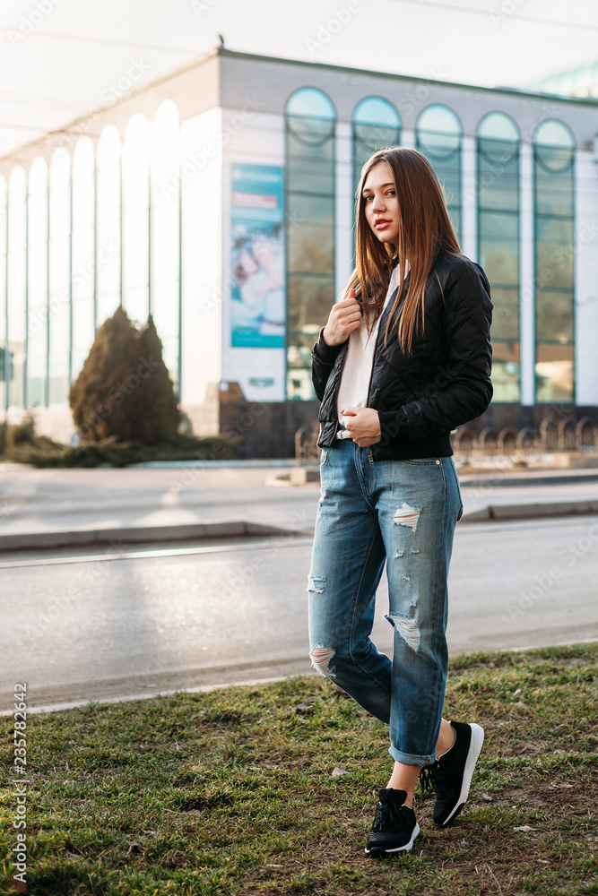 fashion Girl wearing t shirt jeans and leather jacket posing against street urban clothing style. Stock Adobe Stock