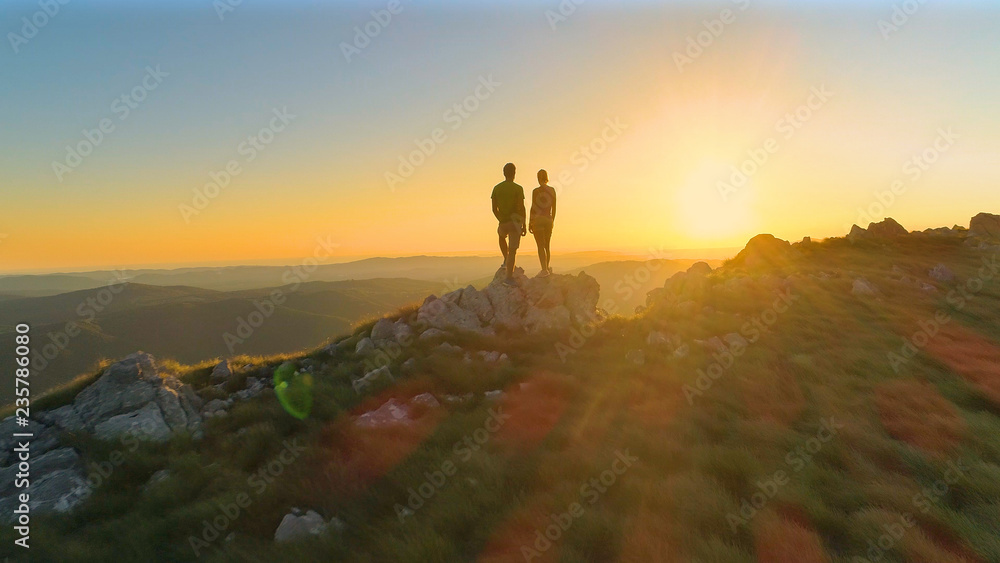 DRONE: Cinematic shot of active young couple observing the evening landscape.