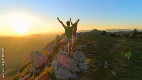 AERIAL: Picturesque nature surrounding couple celebrating a successful hike.