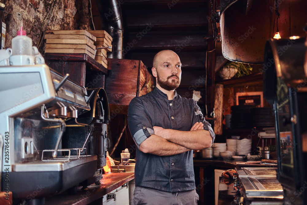 Confident chef posing with his arms crossed and looking away in a restaurant kitchen. Confident chef posing with his arms crossed and looking away in a restaurant kitchen.