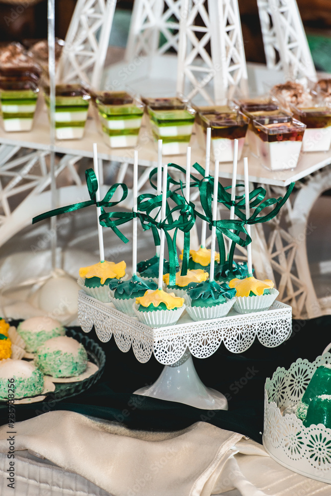 Fototapeta premium green style wedding candy bar on a white table. cupcakes decorated with a green ribbon bow