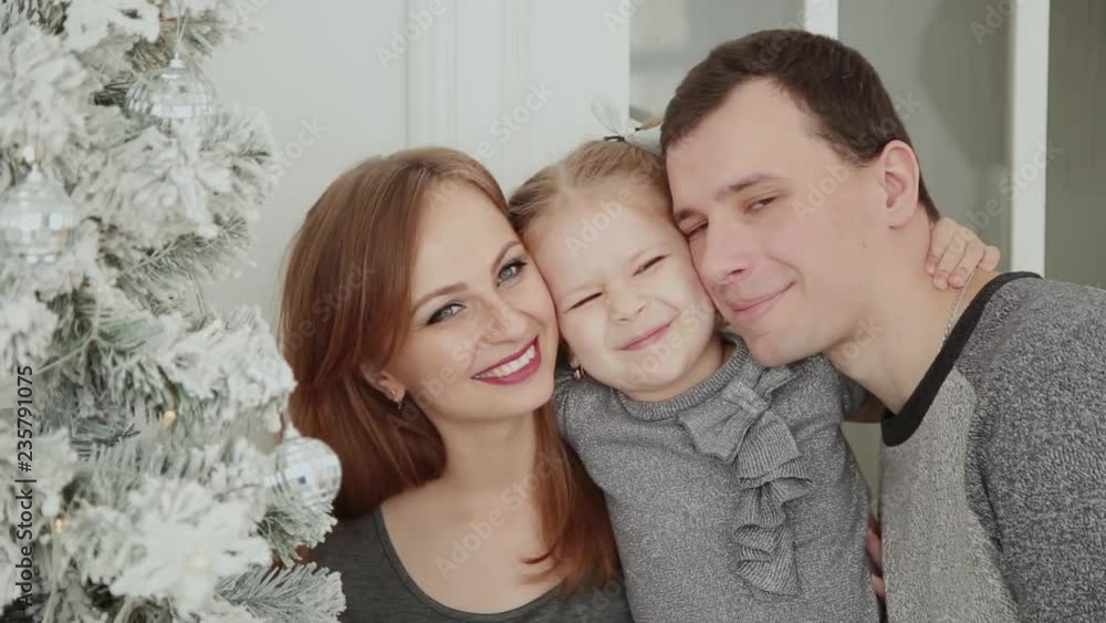 The family is standing near the Christmas tree, laughing talking and touching toys while waiting for Christmas. The family is standing near the Christmas tree, laughing talking and touching toys while waiting for Christmas.