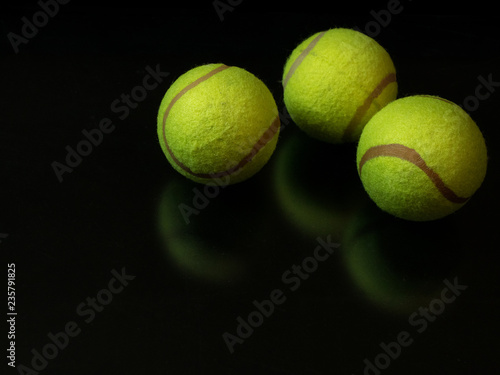 tree tennis balls on dark black background © PabloStock