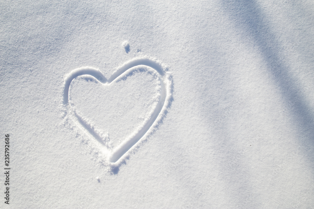 Heart symbol drawn on the white snow on a frosty, sunny winter day. Close-up. Heart symbol drawn on the white snow on a frosty, sunny winter day. Close-up.