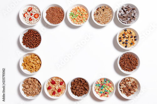 frame of breakfast cereal. bowls of different cereal and cornflakes. isolated on white background. top view. Copy space for your text