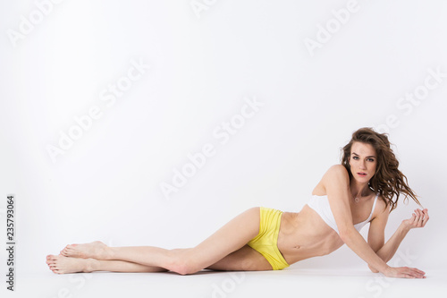 Young sports woman lying on the floor in the studio isolated.