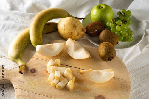 Ingredients for fruit salad. Cutting pears on a cutting board