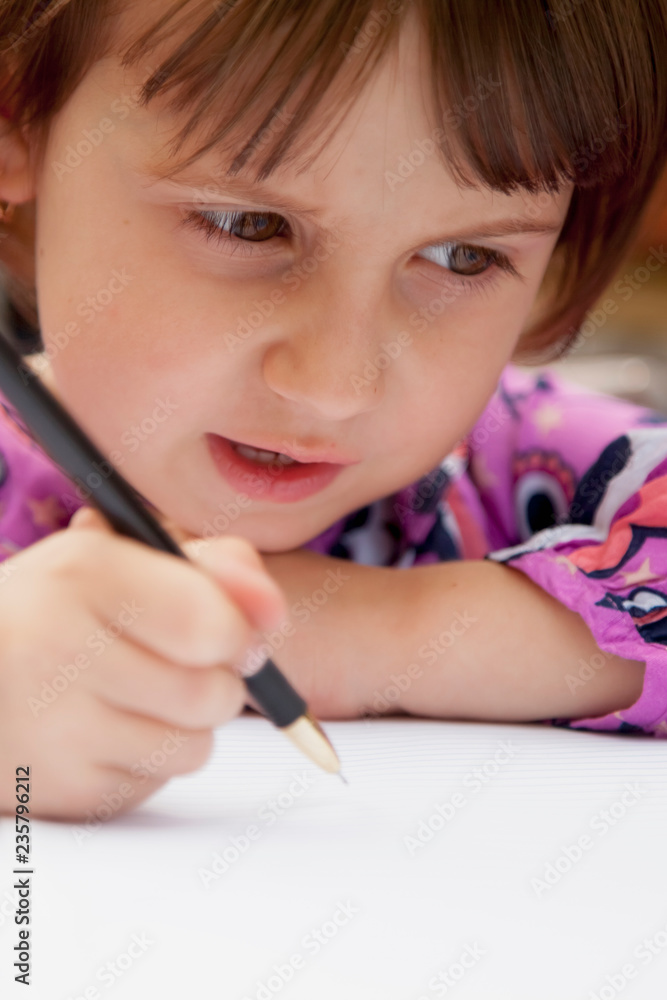 Little beautiful child girl learns to write outdoors. Preschool, development, education concept. Little beautiful child girl learns to write outdoors. Preschool, development, education concept.