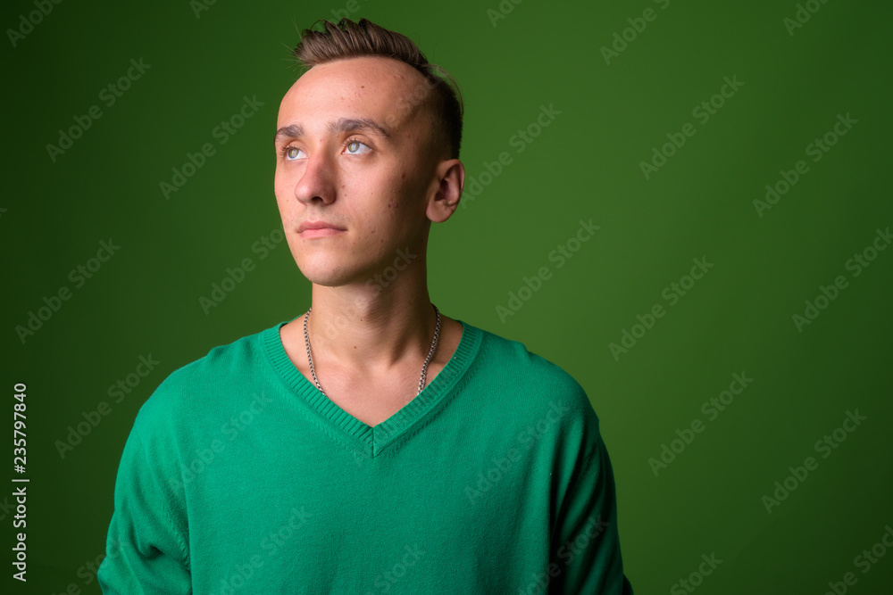 Studio shot of young handsome man against green background Studio shot of young handsome man against green background