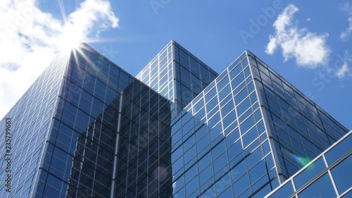 Office building with blue sky, clouds and sun reflecting on peak. Time lapse.