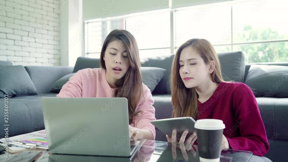 Lesbian Asian couple using laptop making budget in living room at home, sweet couple enjoy love moment while lying on the sofa when relax at home. Lifestyle couple relax at home concept. Lesbian Asian couple using laptop making budget in living room at home, sweet couple enjoy love moment while lying on the sofa when relax at home. Lifestyle couple relax at home concept.