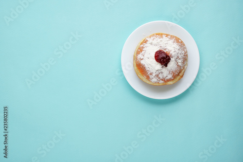 Tradition Jewish holiday sweets, donut sufganioyt with sugar powder and jam on blue background top view with copy space