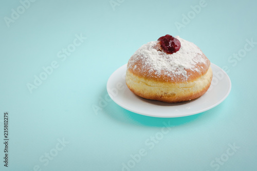 Tradition Jewish holiday sweets, donut sufganioyt with sugar powder and jam on blue background with copy space