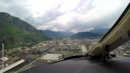 Cockpit view of an aircraft landing at an airport in the mountains on a cloudy day. photo