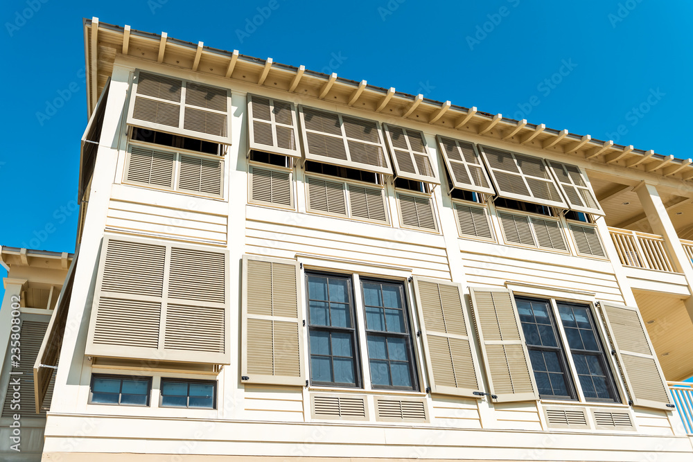 Pastel yellow orange colorful hurricane window shutters architecture open exterior of house in Florida beach home apartment building looking up low angle during sunny day