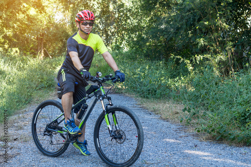 Man with helmet glove for safety riding a bicycle at countryside road along a forest,Cross country riding,cycling activity and sports.