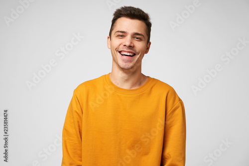 Cheerful positive male youngster, dressed casually, glad to spend time with friends, joking laughing, has a good time. Positive emotions and feelings, isolated over white background