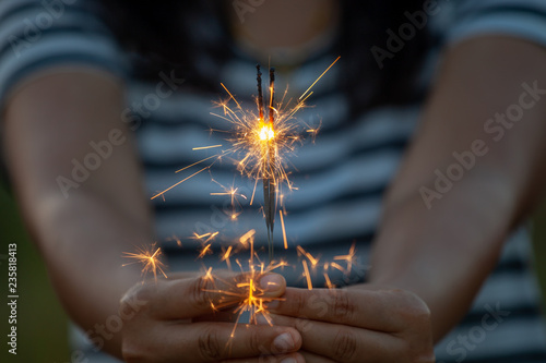 Woman holding and playing with fire sparklers on the festival in the rice field at sunset time