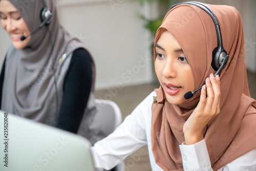 Beautiful Asian muslim woman working  in call center with team photo