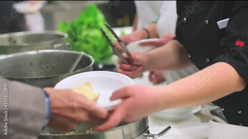 Putting food on the plate. Serving food at homeless shelter. Students canteen