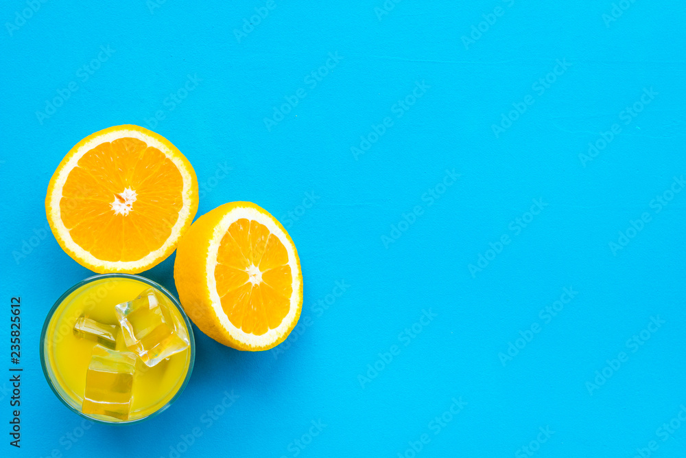 Fototapeta Fresh squeezed orange juice in glass near half cut oranges on blue background top view copy space