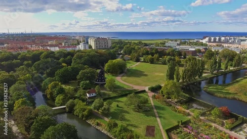 Birds view of going towards an old windmill over the garden in slottsparken, Malmoe, Sweden with oresund in the background in 4k. photo