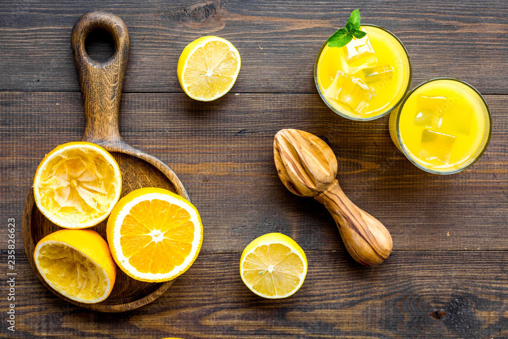 Squeeze fresh oranges with juicer. Orange juice in glass near half cut oranges on dark wooden background top view Squeeze fresh oranges with juicer. Orange juice in glass near half cut oranges on dark wooden background top view