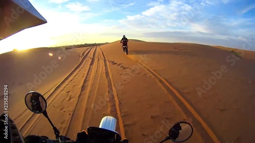 High up on the Dunes of the Moroccan Desert, with the blue and white backdrop, one can see the Dessert from the bikers point of view.