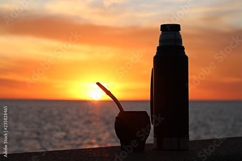 Fotografia Silueta de mate con garrafa térmica apoiada na mureta da Rambla no por do sol as