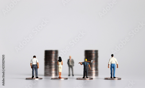 Miniature people with piles of coins. The concept of workers demanding a minimum wage increase. photo
