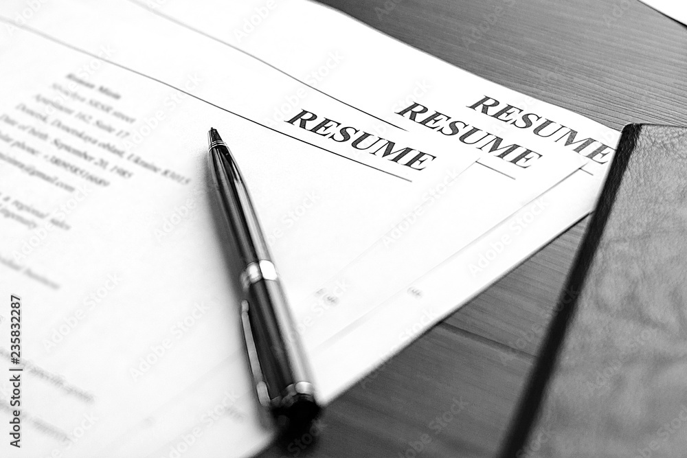 Resume (curriculum vitae, cv) and pen on a written wooden table. Resume (curriculum vitae, cv) and pen on a written wooden table.