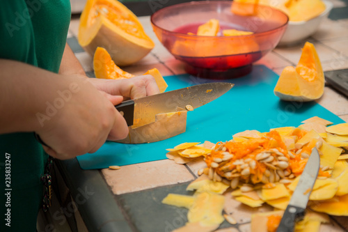 horizontal image with detail of a woman's hand cutting and cleaning a pumpkin