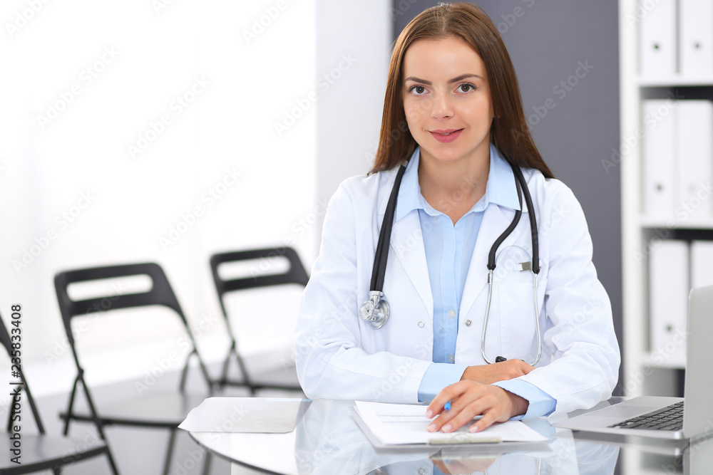 Doctor woman at work. Portrait of female physician filling up medical form while sitting at the glass desk at clinic or hospital. Medicine and healthcare concept Doctor woman at work. Portrait of female physician filling up medical form while sitting at the glass desk at clinic or hospital. Medicine and healthcare concept