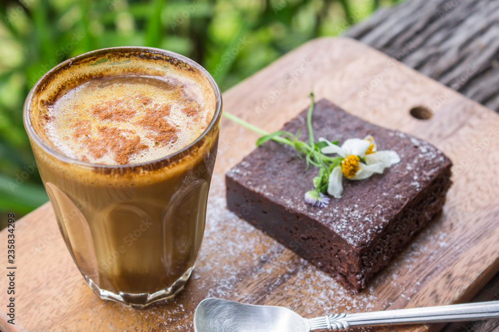 Latte Coffee and Chocolate Brownie Cake and Daisy on Chopping Board on Wood Table Top View Latte Coffee and Chocolate Brownie Cake and Daisy on Chopping Board on Wood Table Top View
