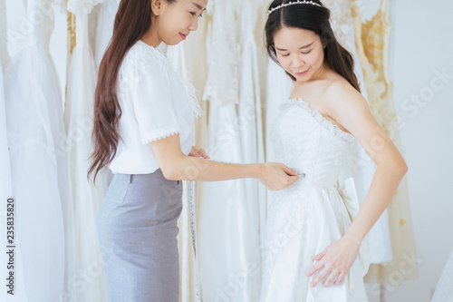 Asian women bride trying on wedding dress,Woman designer making adjustment to her