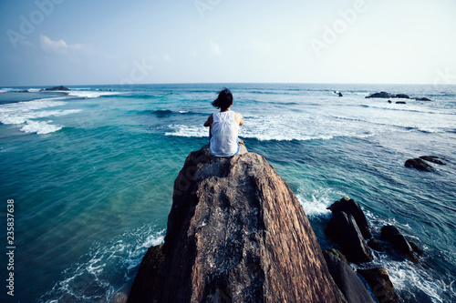 Obraz na plátně Young woman sit on seaside rock cliff edge looking at the distance