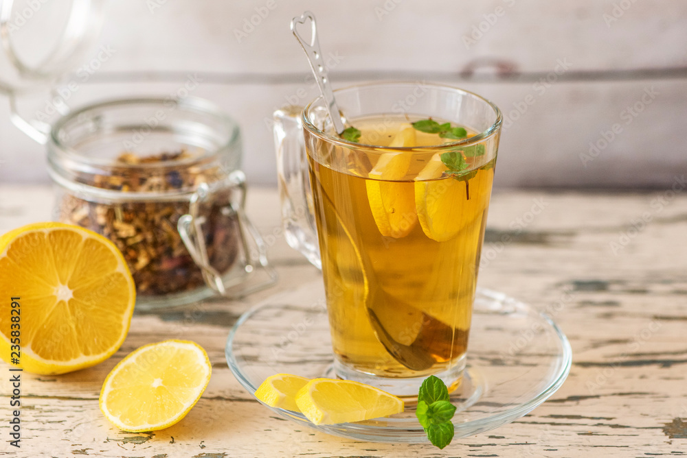 Cup of Lemon tea with lemon slices and mint on light wooden table Cup of Lemon tea with lemon slices and mint on light wooden table