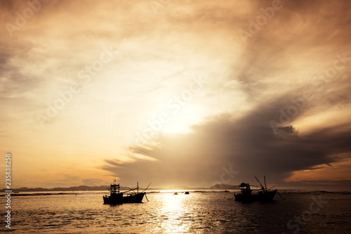 Sunrise over the sea with two fishermen boats in the water